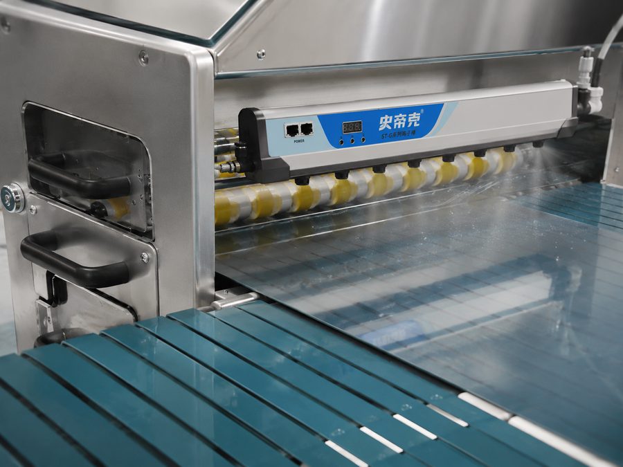 DGSDK ST-G ionizing bar close-up showing emitter needle array and digital display, mounted above conveyor inside cleaning machine